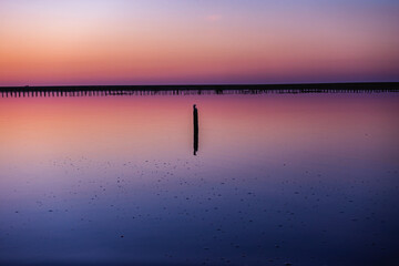 Serene sunset over a salt lake with colorful gradient sky reflected on calm water, featuring...