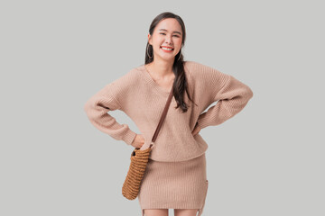 Studio portrait shot of positive Asian woman in casual sweater dress making warm welcome hand...