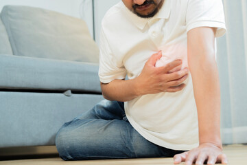 Cropped shot of Asian adult man sit on floor and holding his arms around his chest suffering from a...