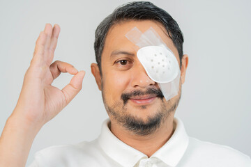 Handsome adult beard man with eye patch showing okay gesture with hand against white background.