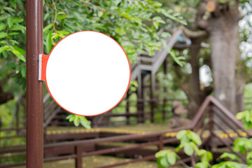 Rustic Wooden Circle Sign Hanging. Round sign on a steel pole in Lush Green Tropical Foliage.
