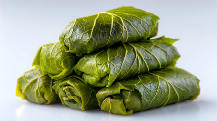 Stuffed grape leaves tightly rolled and stacked on a white surface. Traditional dish made with green leaves filled with rice or meat, known for its fresh and savory taste.