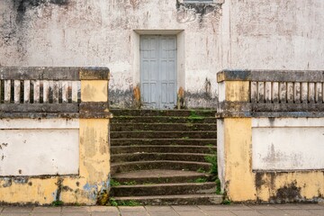 Short flight of worn stone steps leads to a recessed gray door.