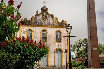Historic church with ornate facade and lush red flowers.