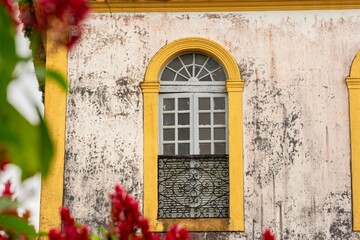 Vintage yellow arched window with wrought iron balcony.