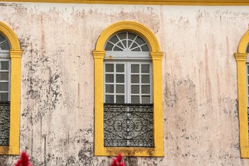 Trio of tall arched windows punctuates a mottled pink wall.
