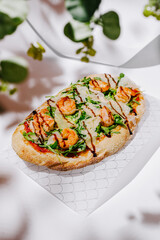 Shrimp flatbread with fresh greens served on a textured surface