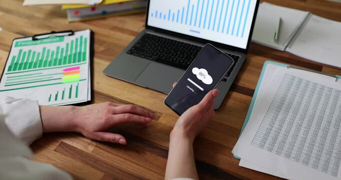 Person taps fingers impatiently while phone shows loading screen. Repetitive movement reflects growing frustration and tension during remote working