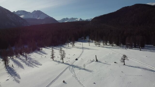 Drone aerial footage of a snowmobile riding across a frozen lake and snowy terrain in Russia. Captured from various angles, this footage highlights winter adventure, remote wilderness