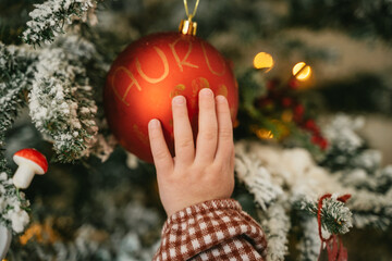 Child Touching Christmas Ornament on Tree Branch
