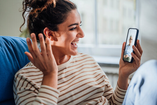 Happy woman video calling grandmother through mobile phone at home