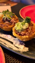 Malaga, Spain - June 16, 2025: Delicious Mexican food featuring two tostadas topped with guacamole, salsa, and fresh cilantro on a decorative plate