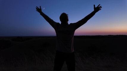 Man with arms wide open enjoying outdoors under stars, planets and Moon.