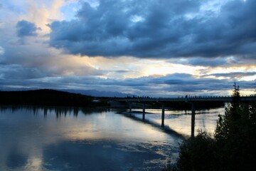 Scenic view of a bridge over a calm river at sunset.