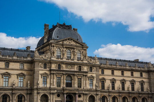 Naklejki The Louvre Museum facade in Paris, France under a cloudy blue sky