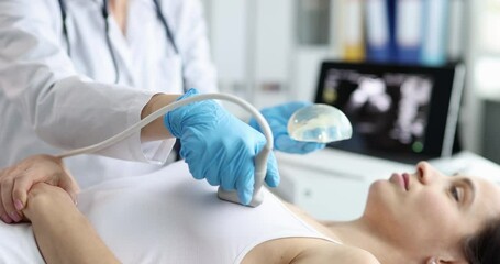 Doctor scans woman breast implants with ultrasound equipment in clinic. Female patient undergoes chest checkup with medical specialist in hospital