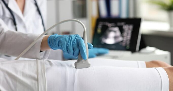 Doctor hand with probe scans woman pelvic organs in modern clinic. Physician checks patient body with ultrasound diagnostic devise in hospital