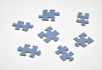 Blue puzzle pieces on a white surface symbolizing teamwork, learning process, and mental health.