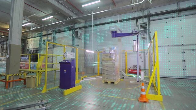 Automatic packaging machine works in the warehouse, automatic palletizer in the warehouse. Packing cardboard boxes in film.