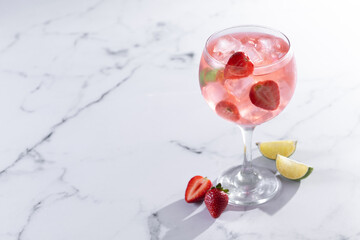 Strawberry gin tonic cocktail on white marble background. Copy space