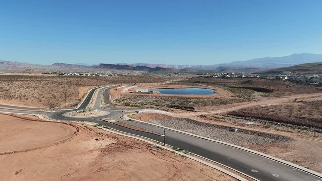 desert development featuring a roundabout, a blue lake, scattered houses, and distant mountains
