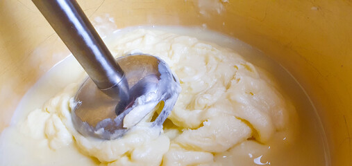 Whipping cream and butter cream with a mixer or blender, preparing cream filling. Mixing butter and cream.