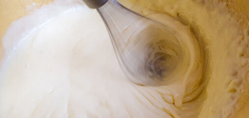 Whipping cream and butter cream with a mixer or blender, preparing cream filling. Mixing butter and cream.