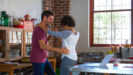 Smiling Couple Having Fun Dancing In Open Plan Apartment Kitchen