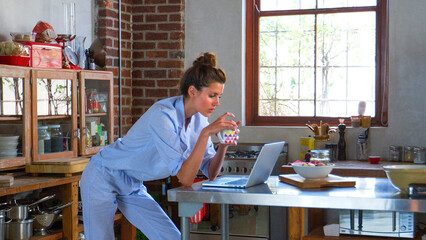 Side View Of Mid Adult Woman Using Laptop In Open Plan Apartment Kitchen