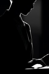 Silhouette of a person working on a laptop.