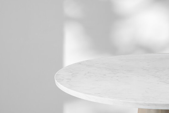 Round marble table top with tree leaves shadow drop on white wall background for mockup product display