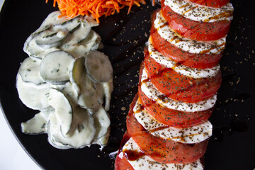 Vegetable platter; with Caprese salad, with tomato and cheese, mozzarella Di Buffalo and basil; there is also shredded carrot salad, and cucumber salad, with vinaigrette cream with mint.