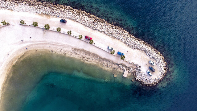 Aerial view of a narrow peninsula extending into the turquoise sea, with vehicles parked along the sandy path, Split, Split-Dalmatia County, Croatia.