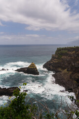 Waves crash against dark rocks along the rugged Madeira coastline, 