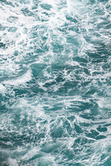 Turbulent turquoise sea with swirling white foam