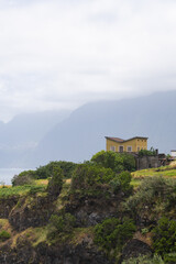 House on green cliff with mountain backdrop Vertical