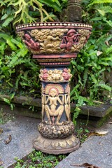 Ornate stone offering bowl in Ubud, Bali, Indonesia. The bowl is decorated with carvings of people and animals, and is used to hold offerings to the gods.