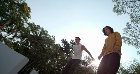Two athletes in a synchronized parkour leap, captured in stunning 1000fps slow motion from a low angle. Experience the dynamic duo's aerial artistry against the Bangkok sky. Concept: dynamic, urban - Powered by Adobe