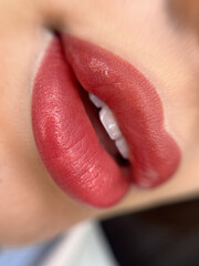 A close-up shot of a woman's lips as she applies a pink-tinted lip balm or lipstick. Her lips are...