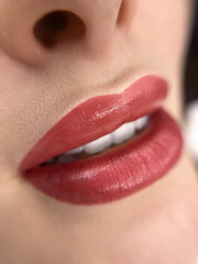 A close-up shot of a woman's lips as she applies a pink-tinted lip balm or lipstick. Her lips are...