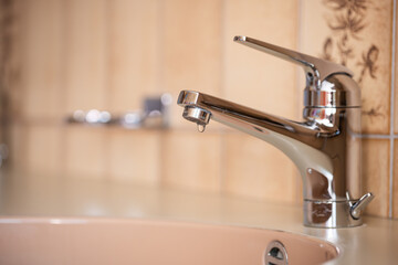 Dripping tap with inside apartment bathroom. Close up shot, shallow depth of field, no people