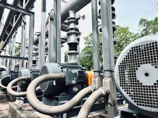 Industrial electric motor pumps installed outdoors with connected pipelines and valves, used in cooling systems, HVAC, and fluid transfer operations in factories or energy plants.
