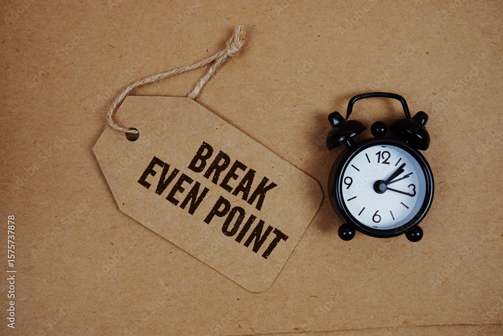 Poster break even point text on price tag with alarm clock on cork board background