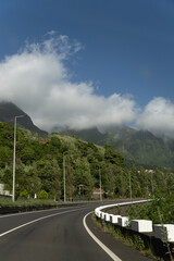 Naklejka premium Curved mountain road with clouds and forest