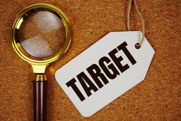 Target text on price tag with magnifying glass on cork board background