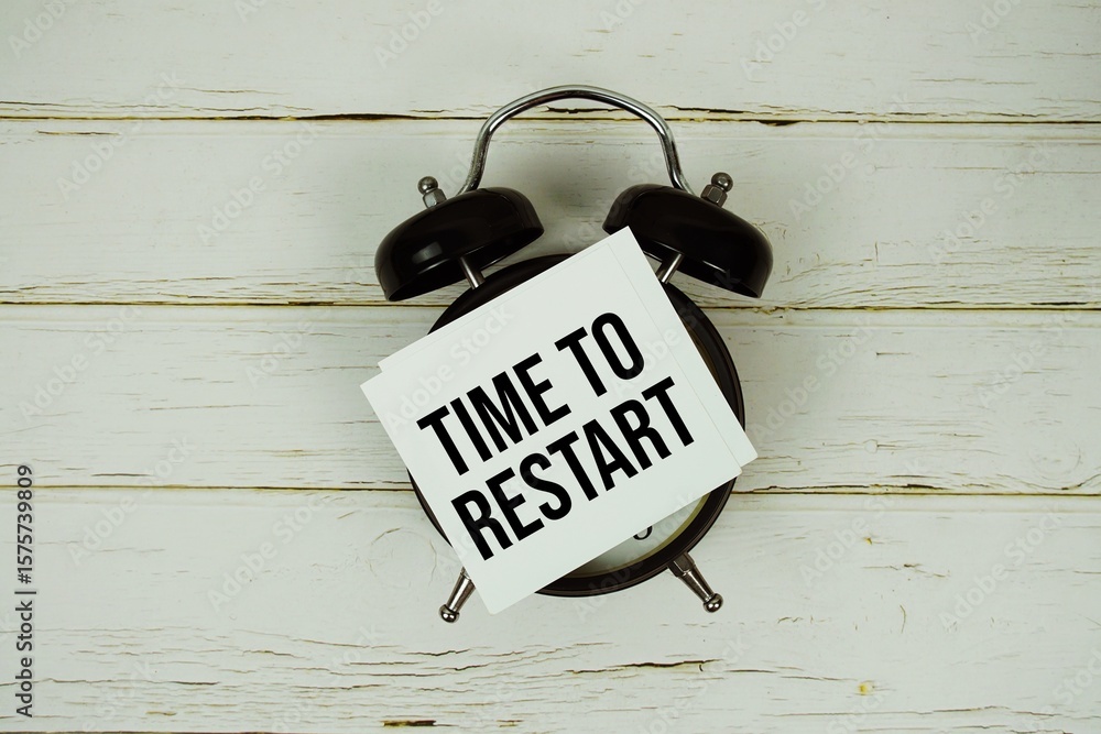 Poster time to restart text message on paper with alarm clock on wooden background