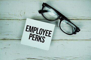Employee Perks text message on paper with eyeglasses on wooden background