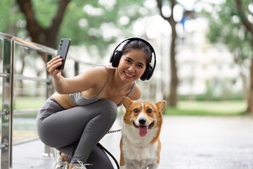 Wellness and Connection. Young woman taking a selfie with her corgi dog in a park.