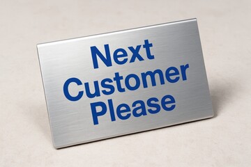 Silver "Next Customer Please" Sign Directs Attention, suggesting efficiency and a welcoming atmosphere in any retail or service environment.