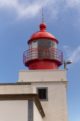 Historic red lighthouse under sunny blue sky vertical